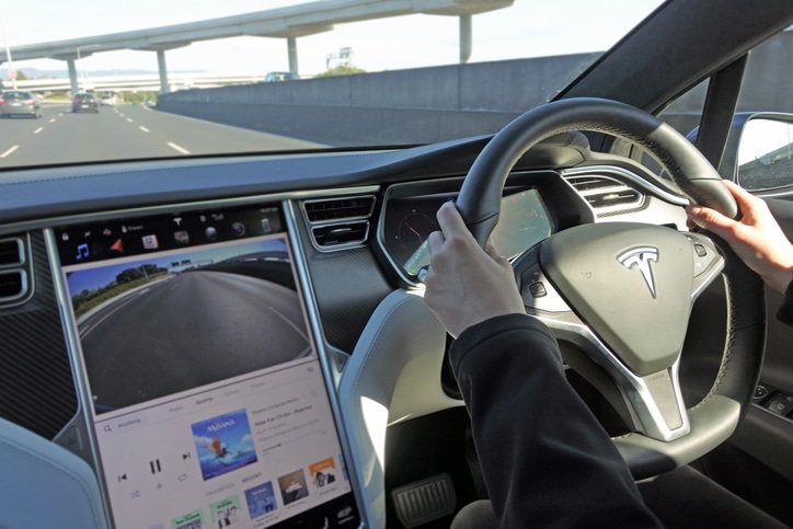 Person driving a Tesla plug-in electric car Model X on a motorway