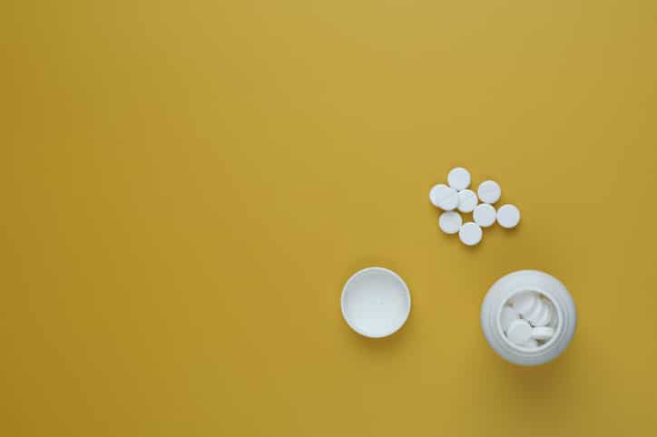 Pill bottle spilling pills onto surface