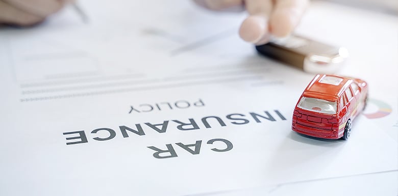 Toy car on top of car insurance papers